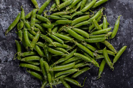 Green pea in a tin, pea pods, scattered pea, branches of pea on black background.