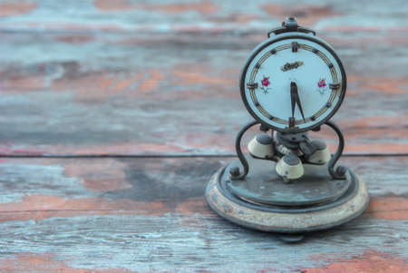 Old retro alarm clock on table with pastel background, on an old wooden table. The time of eternity,...