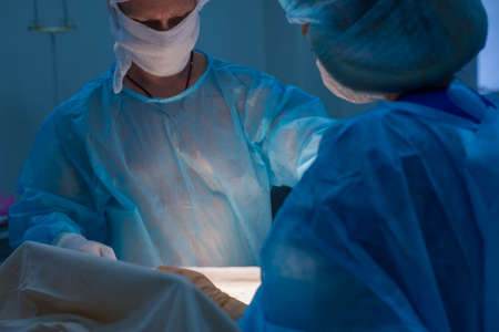 Children's surgeons perform urological operations. A man and a woman in a mask and a blue sterile...