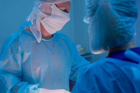 Children's surgeons perform urological operations. A man and a woman in a mask and a blue sterile...