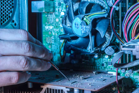 Close-up of professional equipment master repairing computer software. The hand of a master with a screwdriver repairs microcircuit technology. Cleaning computers from dust. Repair equipment. Customer Service Issueの写真素材