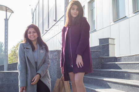 two beautiful smiling Indian girls sisters, with eco shopping bags, amid the hypermarket, go down...