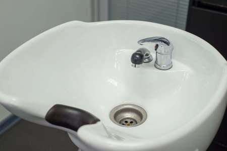 close-up of a male hair care master, washes a mans head in a sink after cutting his hair. Professional male hair care in barbershop. large chair for hairdressers, after cutting, washing hair in the sinkの写真素材