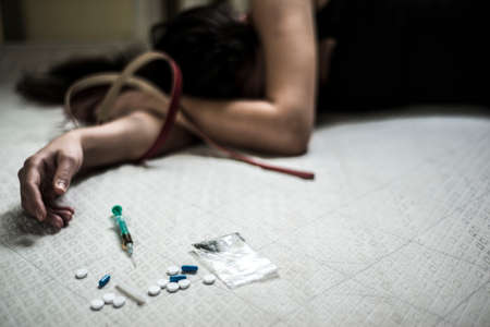 a young girl lies in a dirty brothel on the floor, with an overdose of drugs. Next to the syringe...