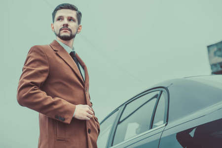 Portrait of a young bearded businessman of thirty years old. In a business style, stands at the...
