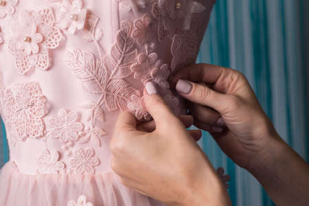 the process of making clothes. Professional designer, handmade craftsman, sews flowers on a pink...