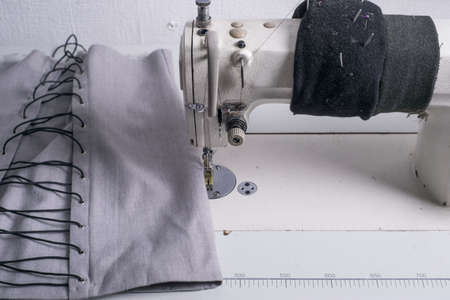 close-up of the hands of a seamstress sewing clothes, sews fabric behind a sewing machineの写真素材