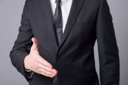 Portrait of a man in a business suit holding out his hand for a handshake. Minimalistic business...