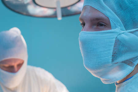 bottom view of surgeons in the operating room, in sterile masks, preparing for surgical...