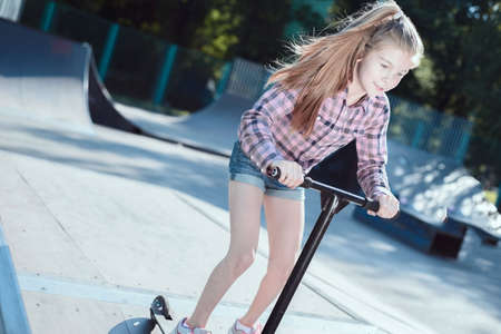 Skater female rides on skateboard at skate park ramp. Young woman practising skateboarding outdoors at skate park.の写真素材