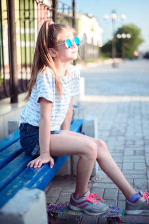 sitting on a bench against the setting sun. Portert beautiful baby girlの写真素材