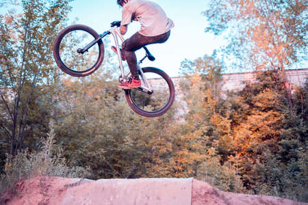 cool stunts performed by a professional cyclist-athlete. In a forest sports field, with ski jumps,...
