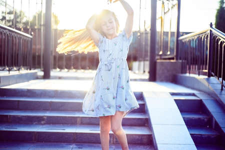 portrait of a beautiful little girl in a dress. Plays with her beautiful hair. Fashionable child,...