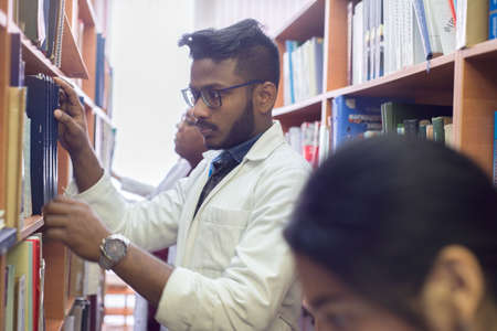 medical university students in a library looking for medical literature. Young people in white coats, mixed race.の写真素材