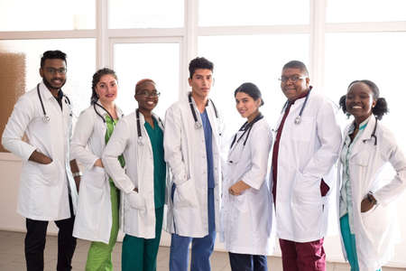 medical students, doctors, mixed race. A team of young people in white coats posing in the hallway...