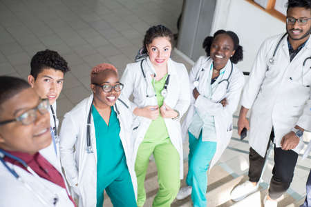 young doctors, mixed race, sitting, standing on the steps, in the corridor of the hospital. They consider x-rays, use gadgets to work in medicine. People in medical clothes.の写真素材