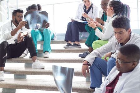 young doctors, mixed race, sitting, standing on the steps, in the corridor of the hospital. They...