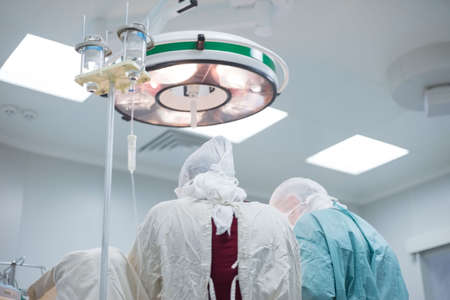 low angle, pediatric surgeons perform surgery in a sterile operating room. The view from the back....