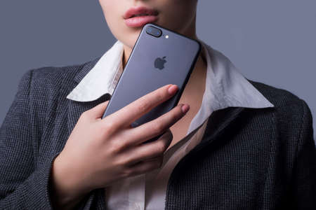 Zaporizhia, Ukraine, December 2019. Studio portrait of a beautiful young girl holding an iPhone near...