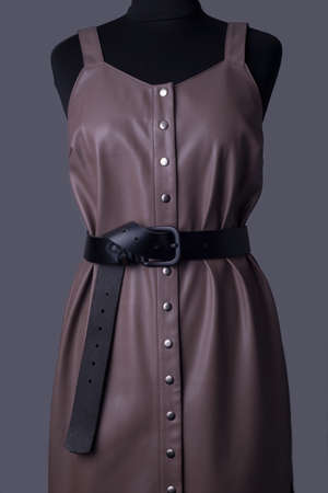 catalog advertising photo of a young red-haired girl in a beige leather sundress from high-quality leather, and a black sweater. On a dark gray background. Style and fashion. Women's leather sundresses coffee colorの写真素材