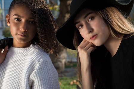 Close up portrait of two young spanish fashion girls. Generation Z. Girl in a black hat, a girl with curly hair. Sisters. girlfriends girls posing for a fashion photo shoot, looking at the camera, beautiful eyes. sexy lesbian coupleの写真素材