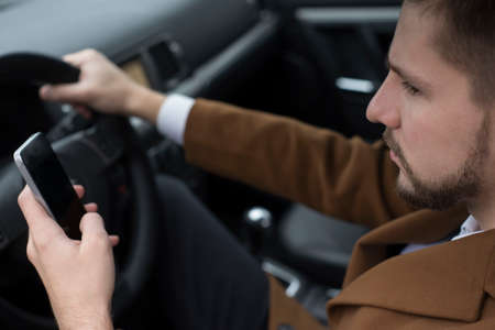 Closeup portrait of a businessman driving a car, in a business suit, looking at the camera. Businessman of thirty years with a beard, office style. goes to workの写真素材