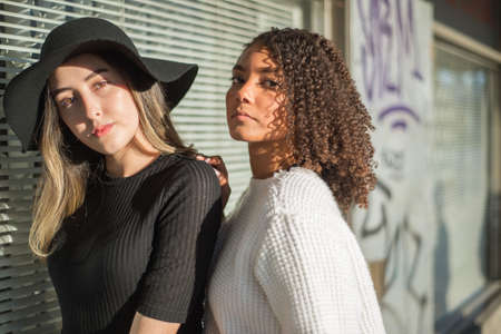portrait of beautiful spanish girls standing together on a background of a shop window. One of the women in a beautiful hat. fashion photo. Street art.の写真素材