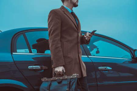 Portrait of a young bearded guy thirty years old. A businessman in a business suit, with a tie, stands against the backdrop of a car. Business concept business style, office style. Business man in a taxi car standingの写真素材