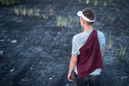 portrait of a young guy, view from the back. Walking on the roof of the building, looking to the side. Fashion photoの写真素材