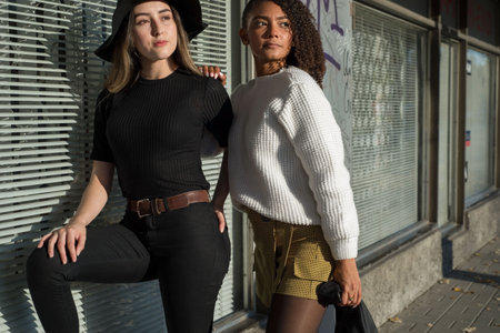 portrait of beautiful spanish girls standing together on a background of a shop window. One of the...