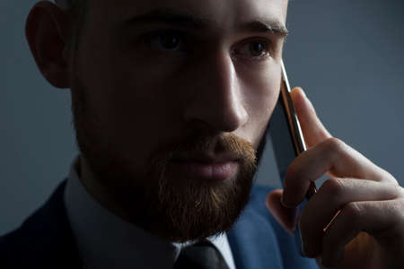 Close-up, studio dramatic portrait of a handsome bearded man, in a business suit, holding a new...