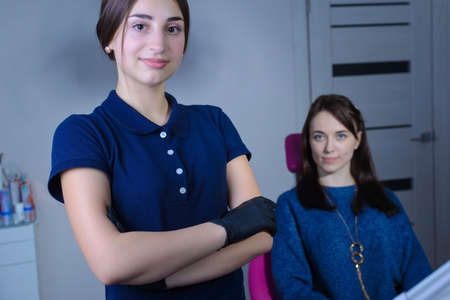 portrait of a young beautiful girl dentist doctor, in mask, smiling, holds dental instruments in his hand, on the background of the patient. At the dental clinicの写真素材