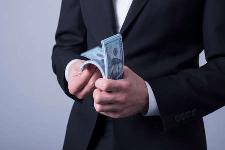 closeup, businessman in a business suit, counts money, holding a press with dollar bills in his...