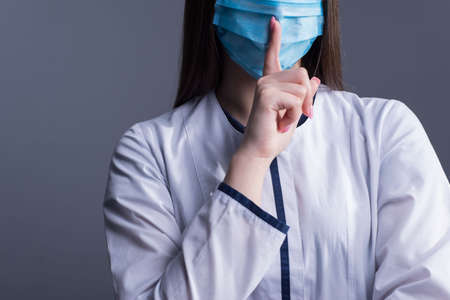 Closeup portrait of a young girl. doctor in a white coat, and a medical mask. looking at the camera....