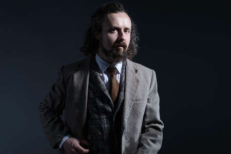 studio dramatic of a young bearded and curly haired guy of thirty years, in an expensive business...