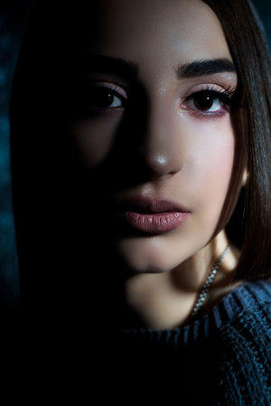 Art studio of a dramatic portrait of a young beautiful girl, with artistic retouching. Close-up, girl's face, with an expressive look. On a dark backgroundの写真素材