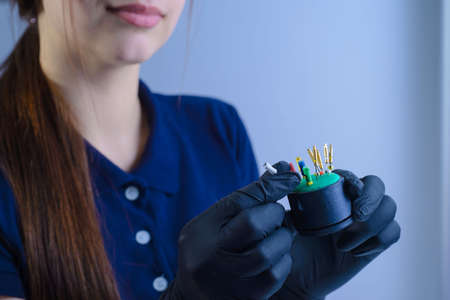 close-up, portrait of the hands of a dentist doctor, using tweezers, in sterile gloves holds tools for the passage of channels in the teeth, dental needles to remove a nerveの写真素材