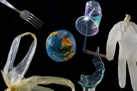 The concept of planet Earth pollution by plastic, metal, polyethylene, glass, rubber, smoke. Around the model of planet Earth, against the background of space,の写真素材