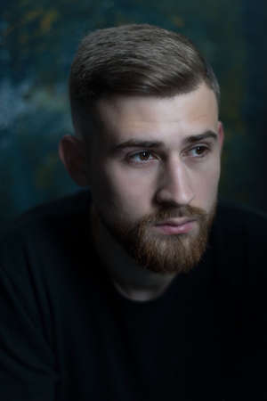 bearded guy portrait of a bearded young guy of twenty-five years old, in black clothes, on a dark...