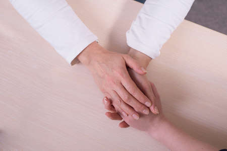 A young hand holding an elderly pair of hands hands of an old woman touch the hands of a young girl,...