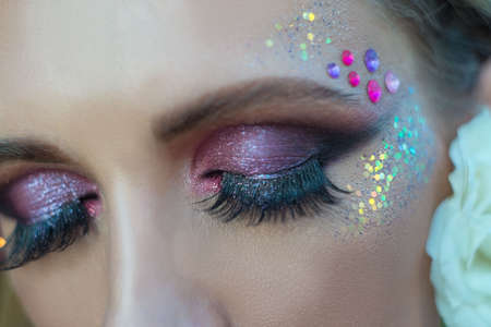 Closeup beauty portrait of creative makeup and false eyelashes of a young female model. Beauty,...