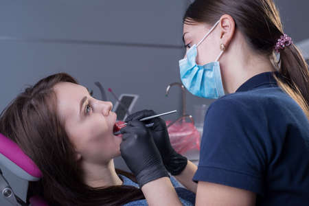 close-up portrait in the dental office. Doctor dentist general practitioner examines a patient using medical instruments. Dental treatment. Cariesの写真素材