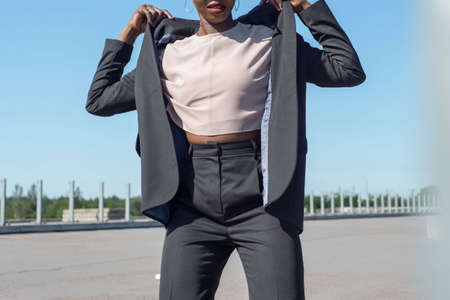 young black girl in a business style, model posing on the street, against a blue sky. fashion and office, business style, office clothes, fashion design, black young girl model, black girl outdoorsの写真素材