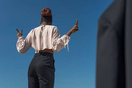 young black girl in a business style, model posing on the street, against a blue sky. fashion and office, business style, office clothes, fashion design, black young girl model, black girl outdoorsの写真素材