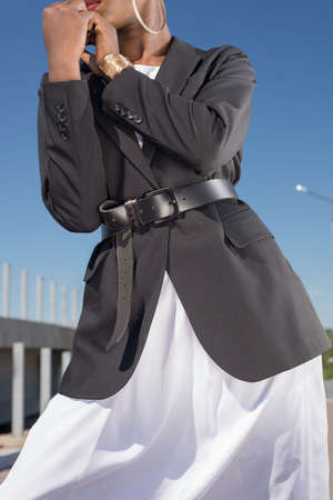 close-up details of a female business black jacket, on a waist a leather belt on an African fashion...