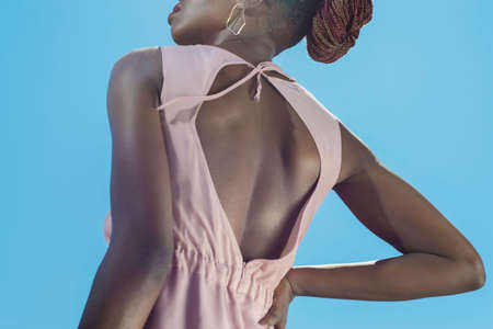 African fashion girl in summer pink overalls, model posing against a blue sky.の写真素材