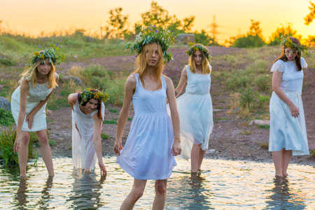 closeup portrait of a young beautiful girl in a white dress, a floral wreath on her head.の写真素材