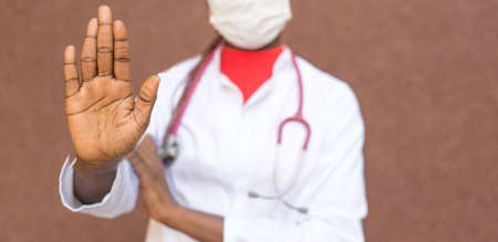 coronavirus stop concept. African American girl doctor, in a protective mask, white coat, shows her...