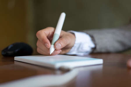 businessman sitting at the table, signs in a graphics tablet with a stylus. Closeup. Business....