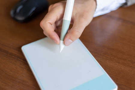businessman sitting at the table, signs in a graphics tablet with a stylus. Closeup. Business....